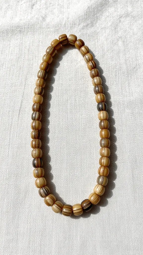 bamboo bead strand casting striped shadow on linen