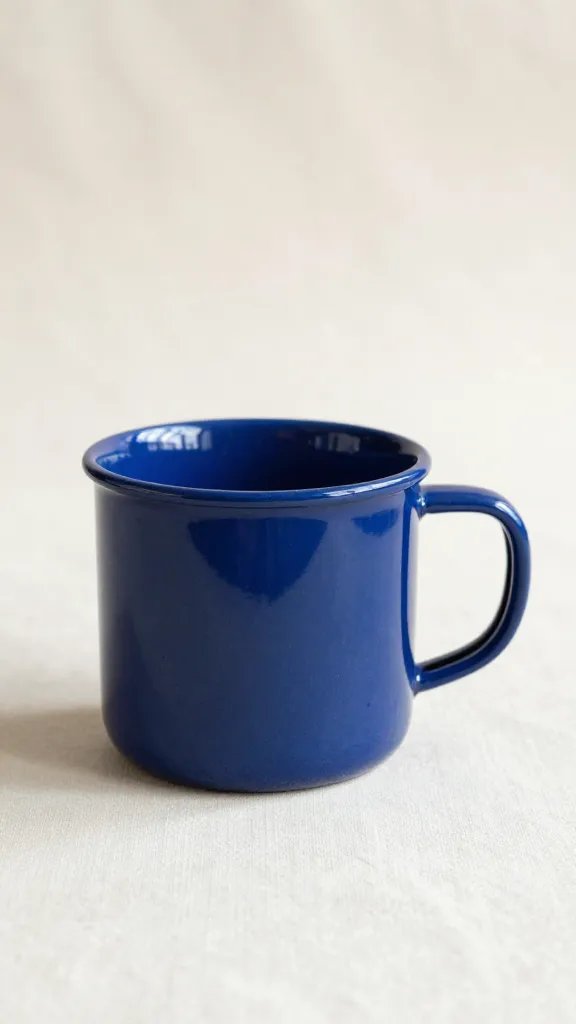 Ink-blue enamel mug on cream tablecloth