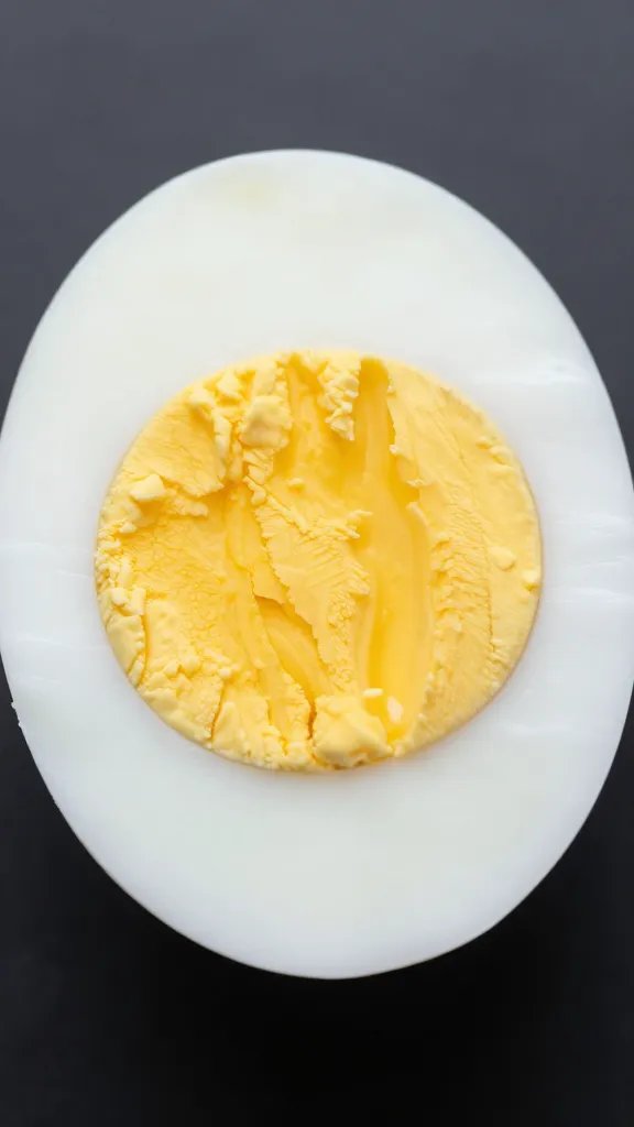 Closeup of a single hard-boiled egg halved to reveal yolk