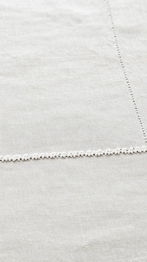 Closeup linen tablecloth texture with delicate embroidered edge
