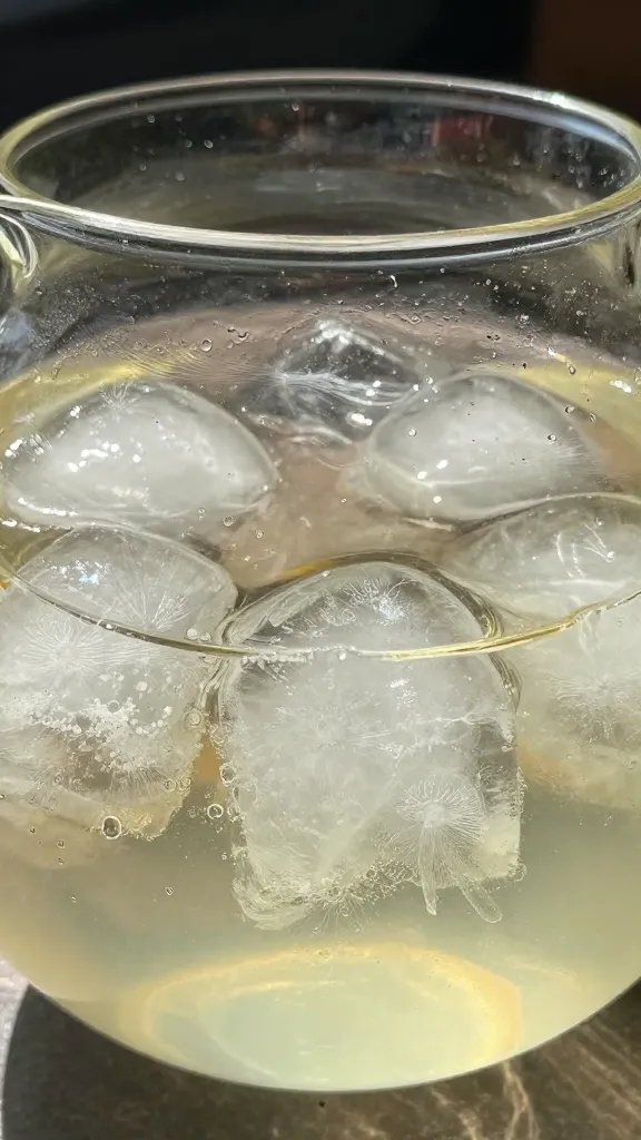 closeup of glass tea pitcher with sunlit ice cubes