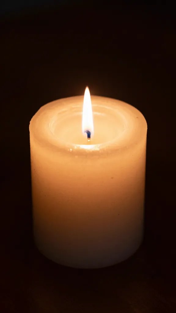 closeup of a candle flame on a shaded grove table