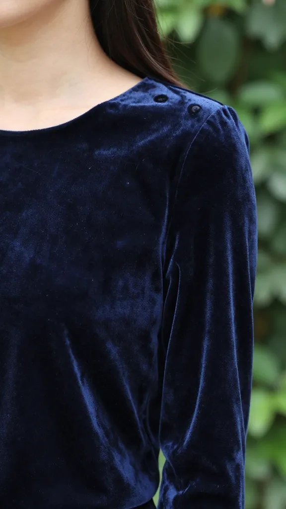 Closeup of a model wearing velvet blouse, lush green blurred background