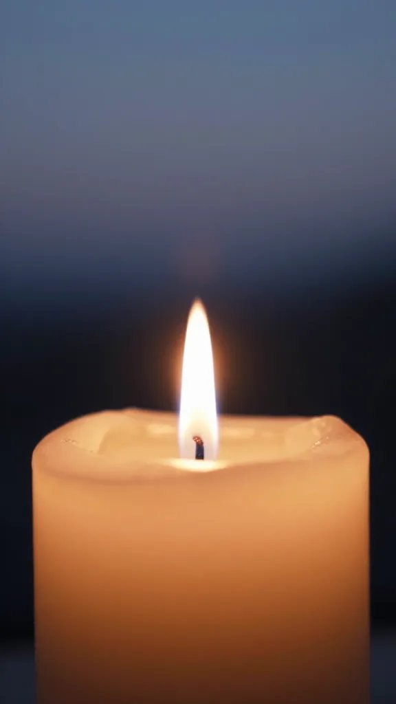 closeup of a solitary candle flame with surrounding twilight blur